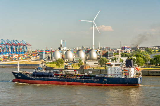 Gas carrier ship in front of harbour terminal with gas reservoir and wind turbine in Hamburg (editorial)