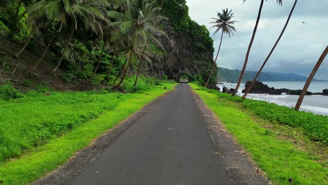 Flying slowly backwards along the Santa Catarina road with the tunnel with the same name in the background at Sao Tome north,Africa