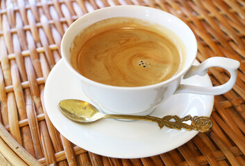 Cup of hot coffee with spoon isolated on rattan table	