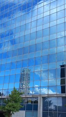 Spiegelung von Hochhäusern in einer moderen blauen Glassfassade