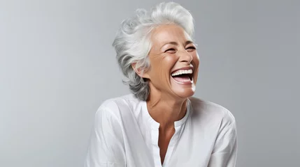 Fotobehang A closeup photo of a elderly senior model woman laughing and smiling with clean teeth on white background © Diana