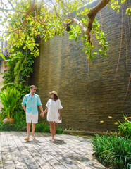 couple vacation luxury resort walking in a tropical garden with green palms and palm trees