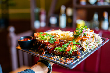 chef or waiter hold Pork ribs with french fries and coleslaw salad