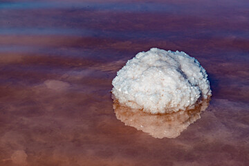 Fototapeta na wymiar Salt Lake. Self-settling sodium chloride salt on rocks near the shore. Hypersaline water