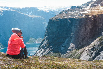 A happy woman on a hike looks at the amazing natural world of the mountains of Norway in the...