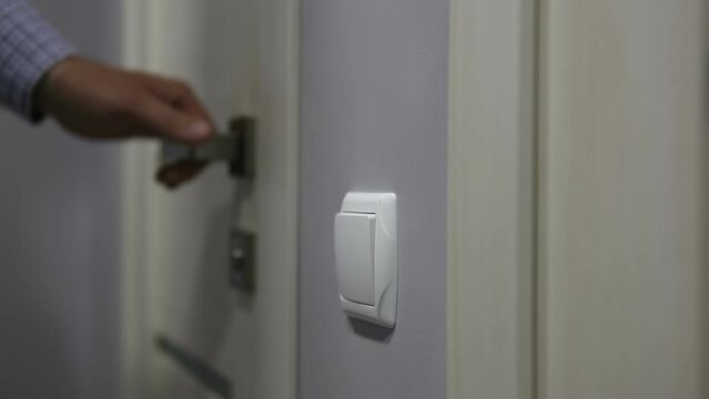 A man enters the toilet room and turns on the light switch on the wall. Looping endless video.