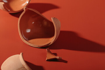 Details of broken ceramic cup on red background. Macro close up of trendy hard shadows from broken...