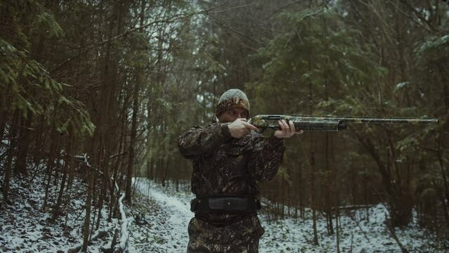 cinematic follow video of a man wearing camouflage aiming and getting ready to shoot an animal in the distance whilst walking slowly and calmly to his target and trying to stay still and composed.