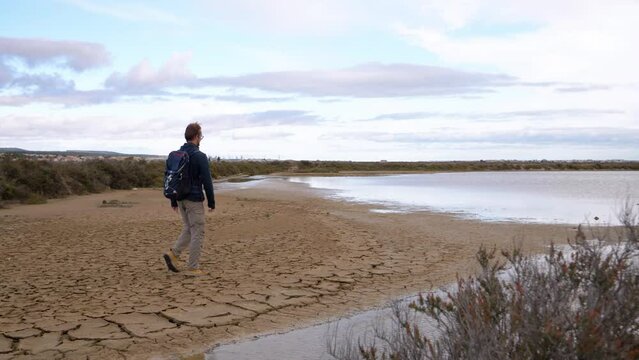 slow motion revealing shot of a man walking along the edges of the Sete salt flats