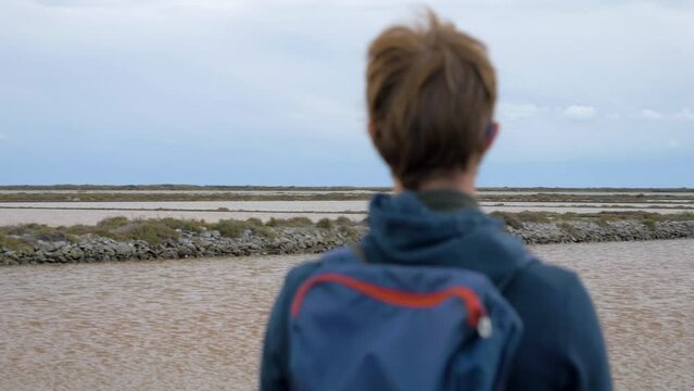 Slow motion orbiting shot of a young man looking out at the Sete salt flats