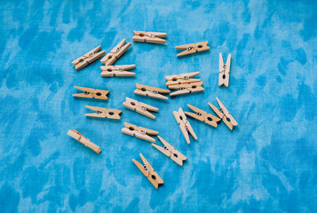 A lot of wooden clothespins lying on a blue fabric background. Photography, household.