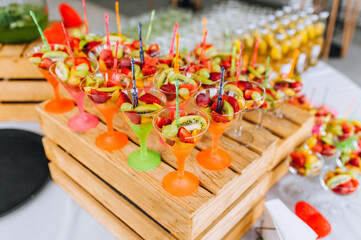 Fresh various fruits are on the table, in a bowl with skewers at the banquet. Food photography, buffet, dessert.