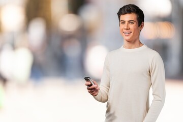 Happy young man checks phone in the street