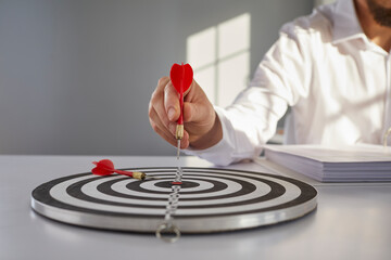 Confident businessman or financial entrepreneur points red arrow right in bulls eye of shooting...
