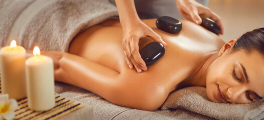 Relaxed young woman enjoying body treatment at wellness center. Beautiful serene girl lying on...