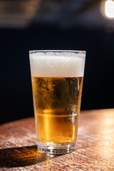 Pint glass of cold fresh british ale and lager beer served in old vintage English pub