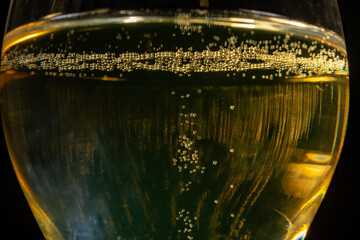 Glass of french sparkling champagne wine with bubbles on dark background, bubbles close up