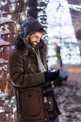 Man typing text message using smart phone while celebrating Christmas outdoors