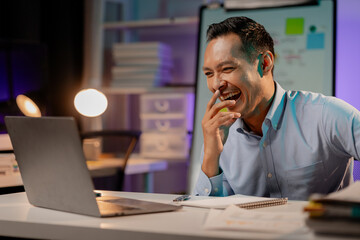 Asian man showing happy expression in the office, company employee working overtime, working late at night, working overtime of a busy and hardworking company employee. Overtime concept.