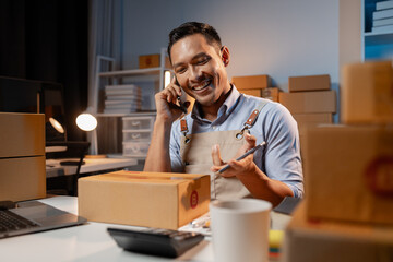 A business owner sells products on websites and online platforms. He is on the phone with a customer to confirm an order, packs the product into a parcel box for delivery with a courier service.