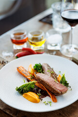 Duck fillet with sweet potato cream, roasted carrots, kale, beet-port sauce on white plate. Grilled and roasted poultry closeup served on a table for lunch in modern cuisine gourmet restaurant. - 648110663