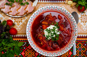 Ukrainian traditional food red borsch on the table with ukrainian ornaments.