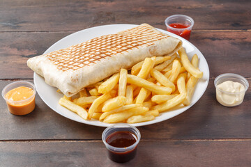 Tacos français sur une assiette avec des frites et sauces. 