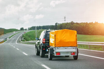 SUV and Rental Cargo Trailer on a Road. Efficient moving. - obrazy, fototapety, plakaty