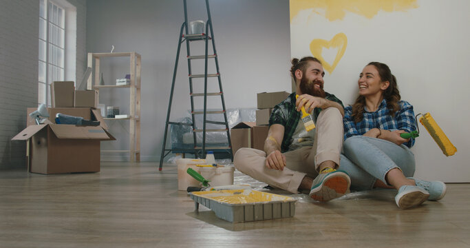 Cheerful young couple in the morning at home. Newlywed caucasian couple are relaxing during renovation of their new home and positively smiling - new life, mortgage concept