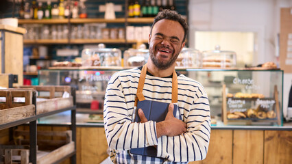 Smiling Man With Down Syndrome Working In Food Shop Using Digital Tablet