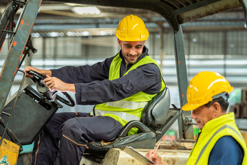 Portrait of forklift truck driver man smiling in old factory warehouse lifting pallet in storage...