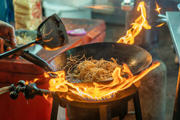 fried noodles cook in pan with big fire flame is hong kong style. Pad Thai favorite and famous...
