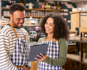 Woman Using Digital Tablet Working In Food Shop Training Man With Down Syndrome