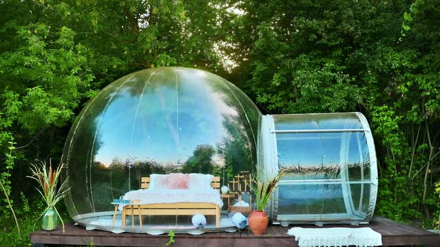 View of a transparent bubble tent at glamping with furniture inside. Nature around