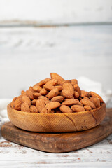 Almond in wood bowl. Roasted almonds on white wood background. Close up