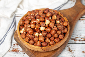 Hazelnuts in wood bowl. Hazelnut kernel on white wood background. Close up