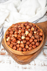 Hazelnuts in wood bowl. Hazelnut kernel on white wood background