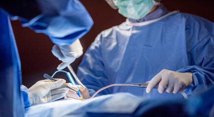 Team of surgery doctor in Operating Room, Assistant Hands out Instruments to Surgeons During...