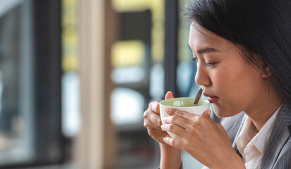Banner of Asian woman Proprietor holding hot coffee in white ceramic cup to sniff smell of espresso in office work place . business owner entrepreneur girl carry coffee break to sniff fragrant smell - obrazy, fototapety, plakaty