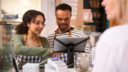Woman Working In Food Shop Training Man With Down Syndrome How To Use Checkout
