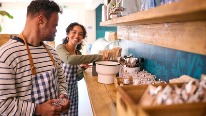 Woman And Man With Down Syndrome Working In Coffee Shop Or Restaurant