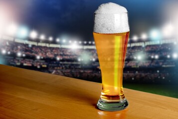 Glass of fresh cold alcohol beer on stadium background
