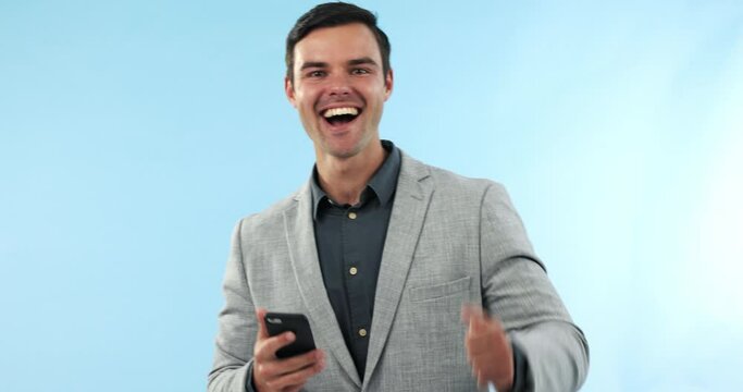 Celebration, phone and face of businessman in a studio with fist pump for success or achievement. Happy, excited and portrait of male winner with online bet victory with cellphone by blue background.