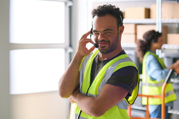 Man With Down Syndrome Working In Warehouse Wearing Headset