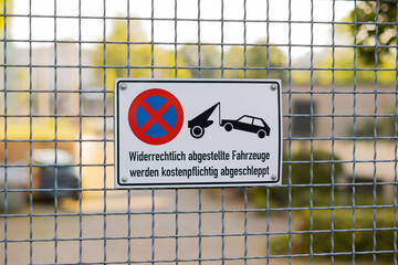Sign on a property entrance saying that parking is prohibited and cars will be towed away. German...