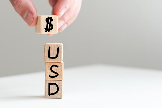 Monetary units : USD text written on wooden block with stacked coins isolated on white background