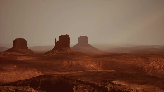A stunning aerial view of a desert landscape with majestic mountains and rugged rock formations in the distance