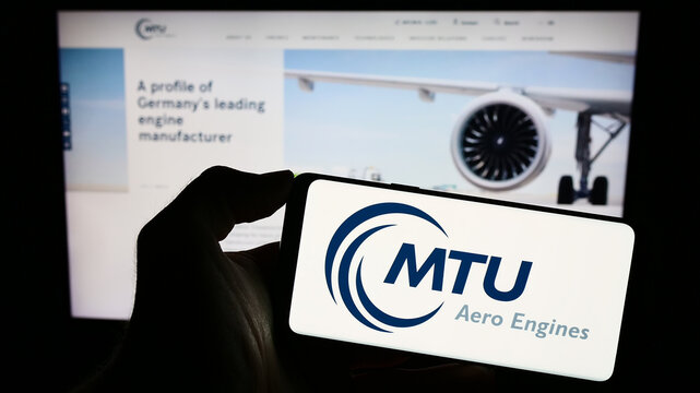 Stuttgart, Germany - 09-10-2023: Person holding smartphone with logo of German aviation company MTU Aero Engines AG on screen in front of website. Focus on phone display.