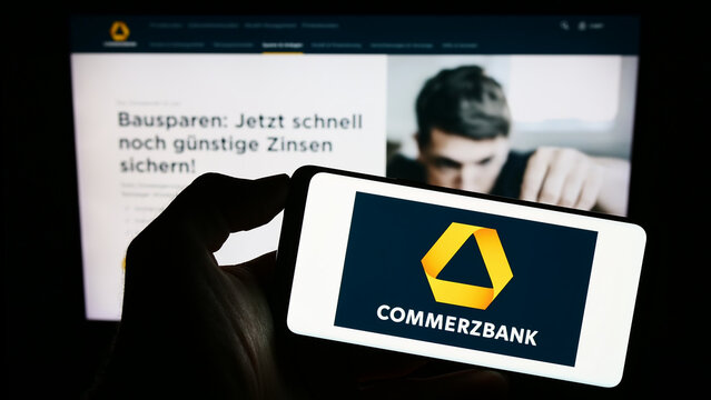 Stuttgart, Germany - 09-10-2023: Person holding cellphone with logo of German financial company Commerzbank AG on screen in front of business webpage. Focus on phone display.