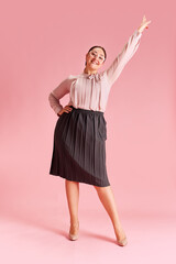 Full-length image of elegant happy woman in her 30s wearing official clothes and glasses against pink background. Success. Concept of business, beauty, human emotions, lifestyle, fashion, ad